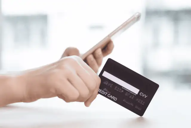 pessoa segurando um celular e um cartão para representar banco digital para cartão de crédito